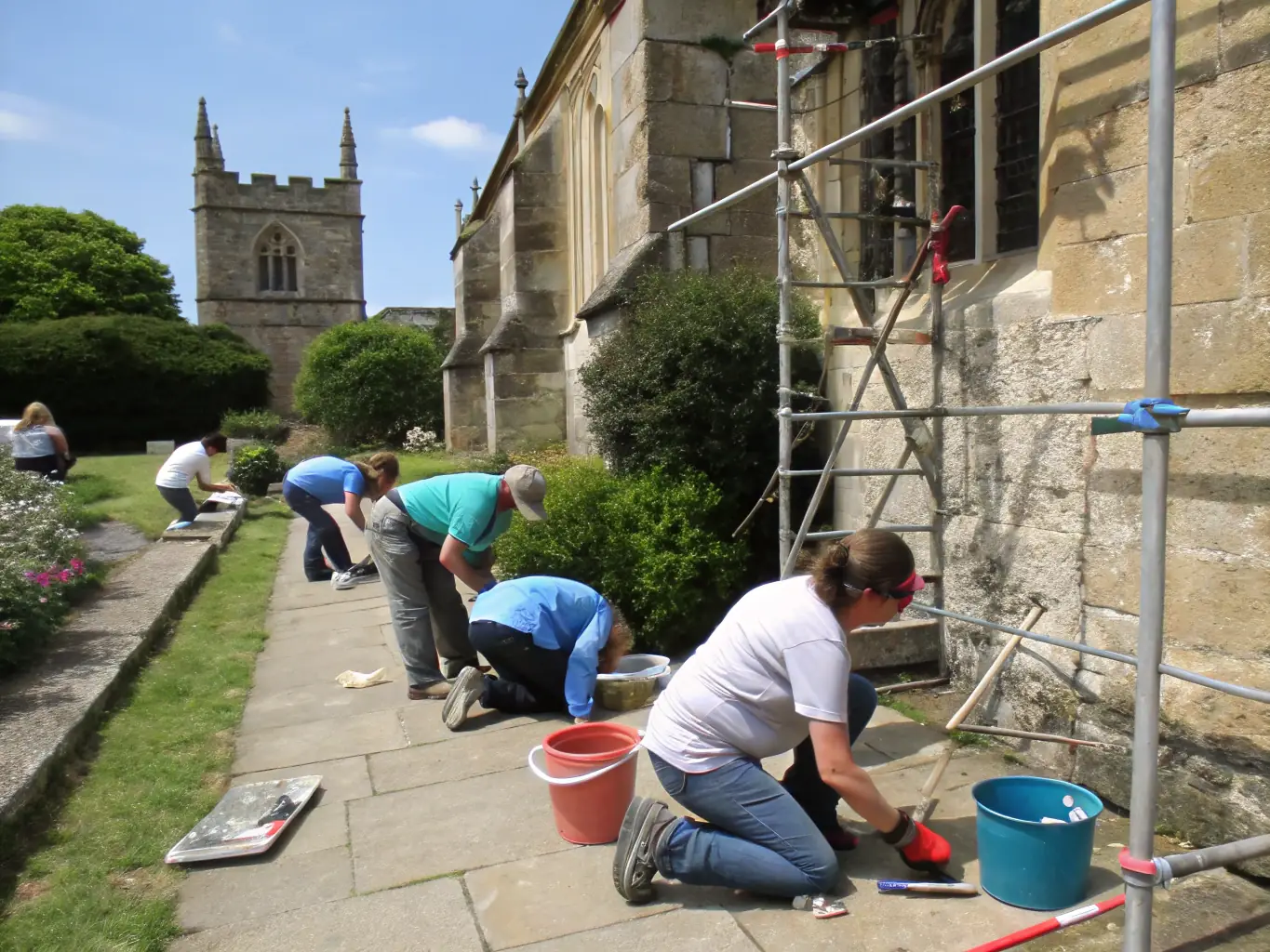 A vibrant image of volunteers working on restoring an old historical building, with scaffolding and preservation tools visible, showcasing the organization's commitment to heritage renovation.
